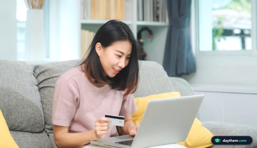 Phụ nữ châu Á ngồi sofa dùng laptop và cầm thẻ tín dụng thanh toán