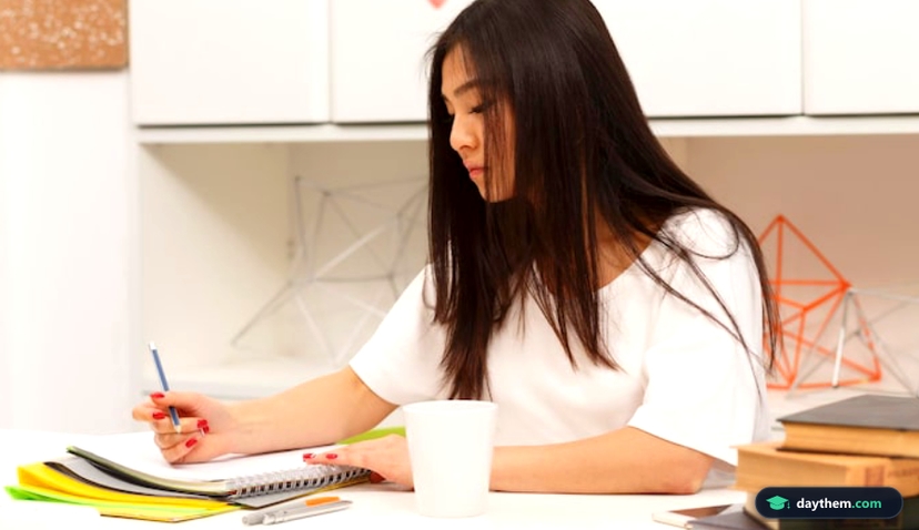 Portrait of brunette Asian student writing something in her exercise-book