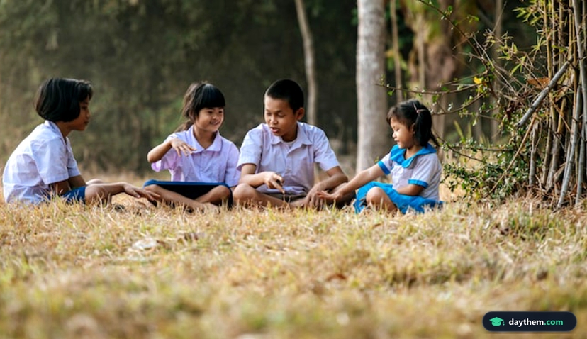 Học sinh mặc đồng phục ngồi trên bãi cỏ chơi đùa vui vẻ
