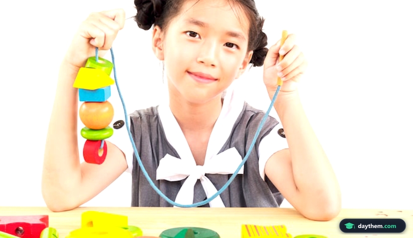 Bé gái châu Á đang chơi đùa với các khối hình học bằng gỗ đầy màu sắc
