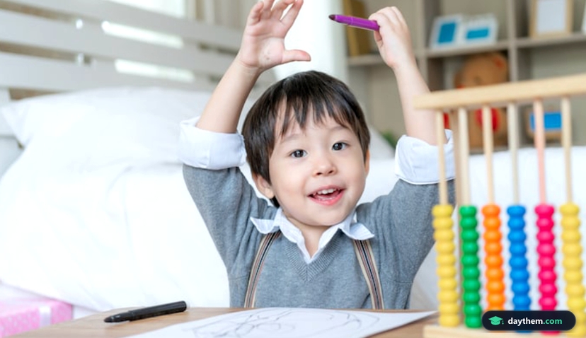 Bé trai mỉm cười tự hào, giơ hai tay lên đầu sau khi hoàn thành bức vẽ