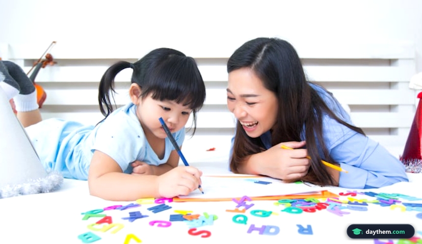 Mẹ và con gái cùng nhau học bảng chữ cái với các thẻ flashcard chữ cái tại bàn học.