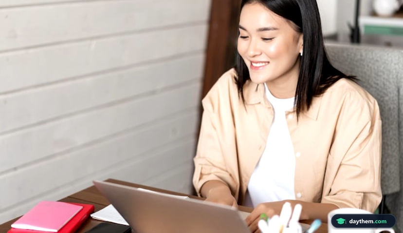Phụ nữ châu Á mỉm cười sử dụng laptop học tập và làm việc trực tuyến tại Trường Đại học Mở TP.HCM